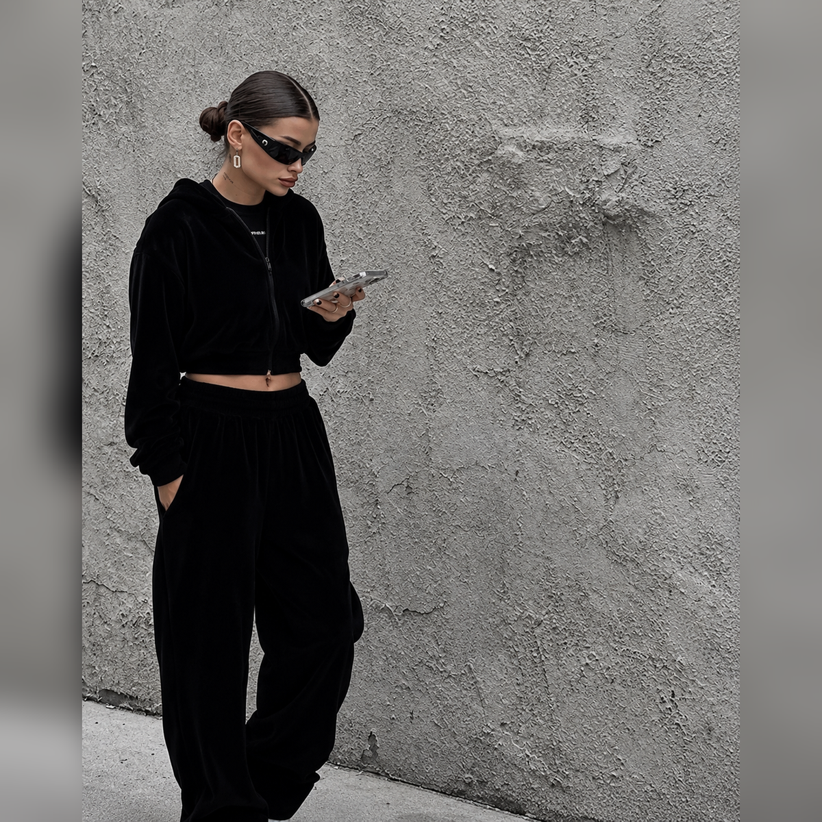 Black two-piece tracksuit with cropped zip hoodie and loose baggy pants styled with sunglasses