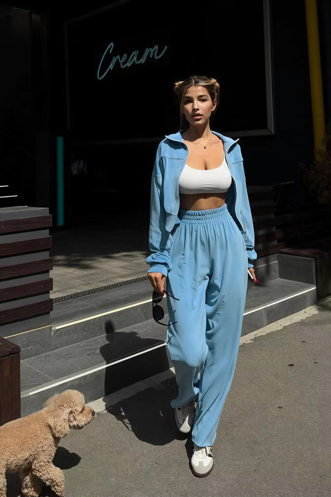 Sky blue cropped track jacket and relaxed wide-leg pants styled outdoors with sneakers