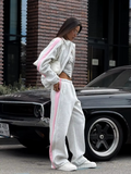 Gray striped tracksuit with pink side panels and relaxed wide-leg pants styled outdoors
