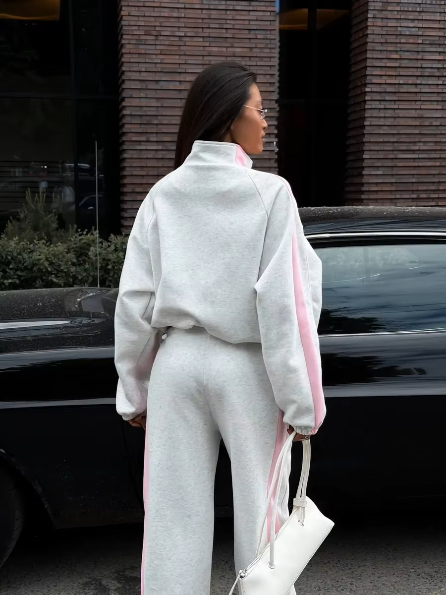 Back view of gray tracksuit with pink sleeve and pant side stripes and relaxed sporty fit