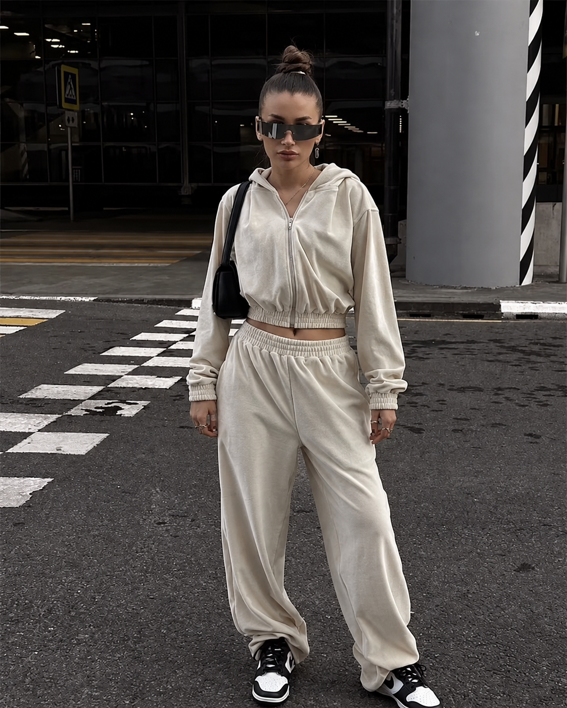 Ivory two-piece tracksuit with cropped zip hoodie, loose full-length pants and black shoulder bag