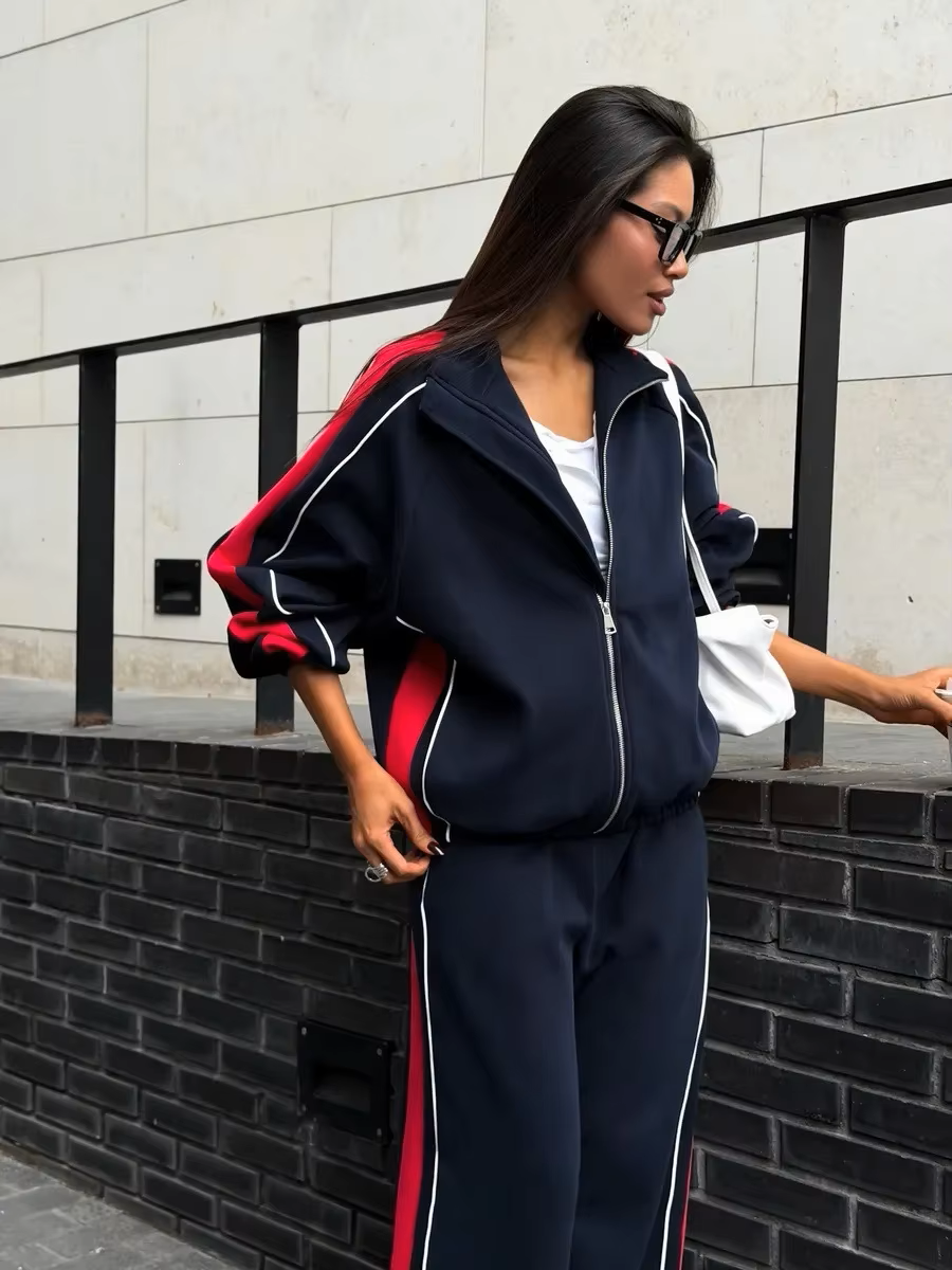 Navy and red striped tracksuit set with zip track jacket and relaxed wide-leg pants styled outdoors