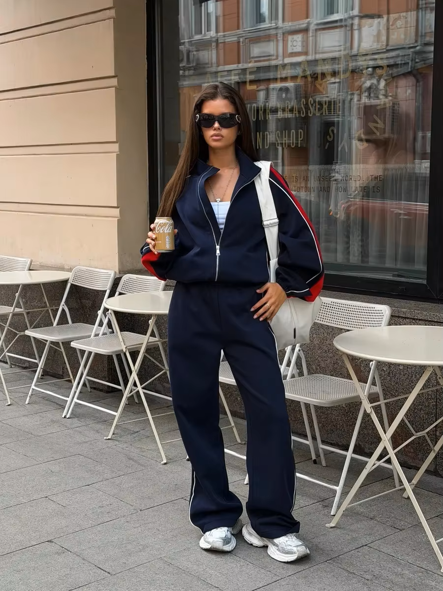Navy and red striped tracksuit set with zip track jacket and relaxed wide-leg pants styled outdoors
