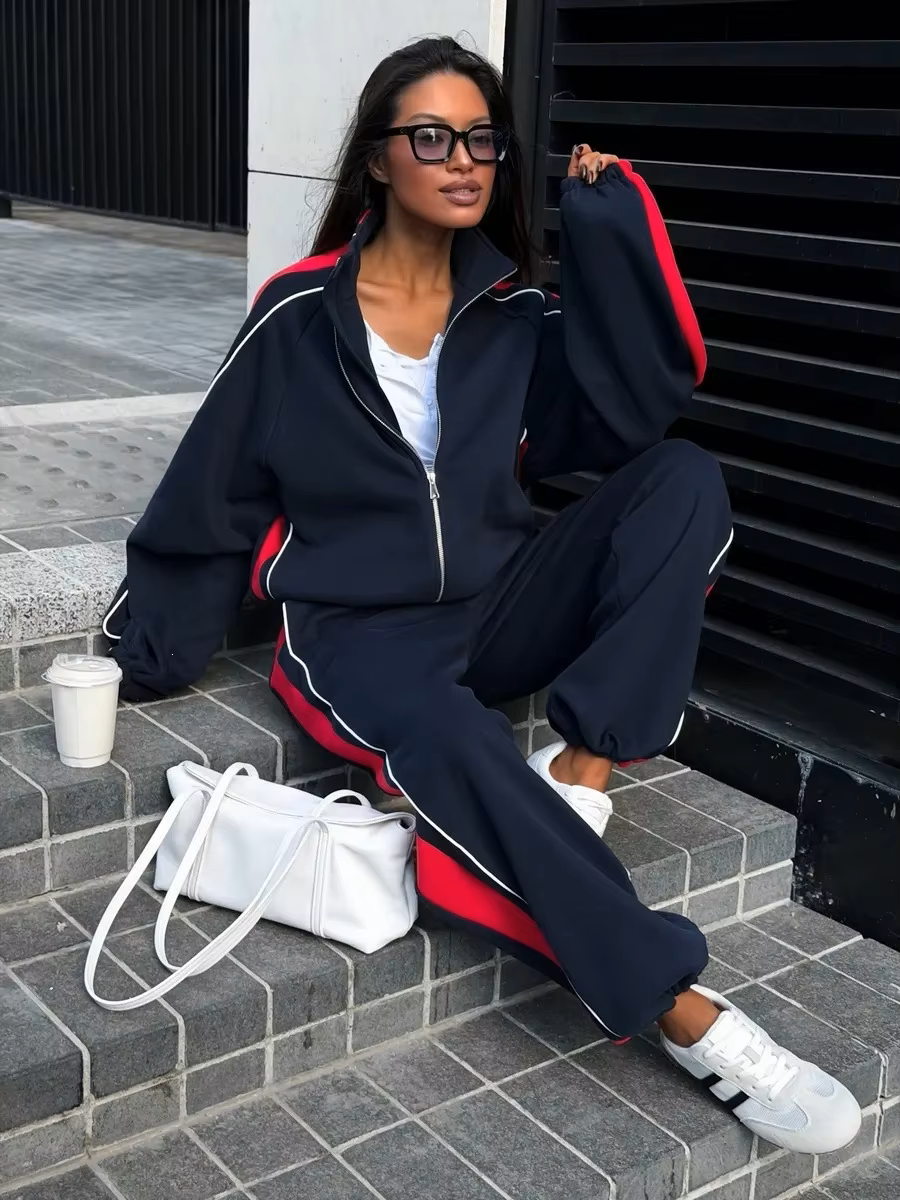 Navy and red striped tracksuit set with zip track jacket and relaxed wide-leg pants styled outdoors