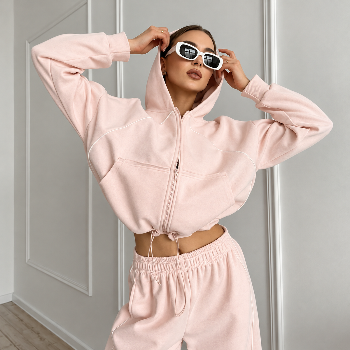 Pink zip-up hoodie tracksuit close-up with roomy hood, piping detail and relaxed sleeves