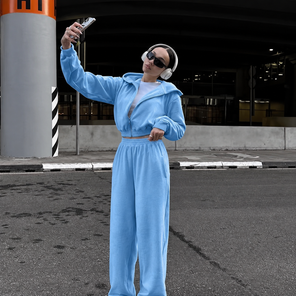 Light blue cropped zip hoodie and baggy pants tracksuit styled with headphones and sunglasses