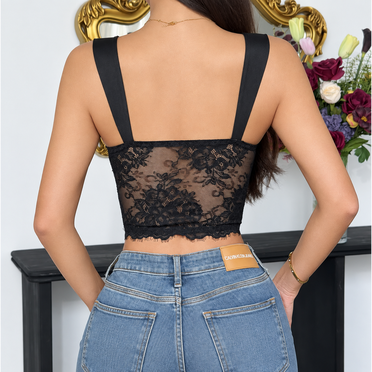 Back view of black lace corset top showing wide shoulder straps and sheer floral lace back